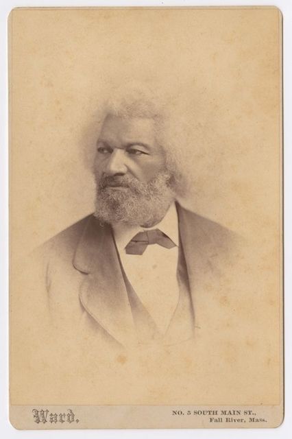 Portrait of a man in a suit and a white afro with his head turned to the right in profile